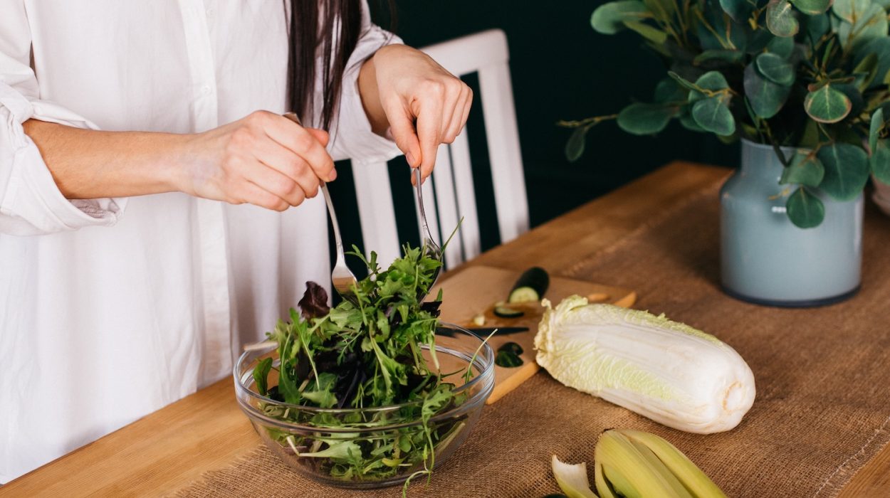 Τα χέρια μιας νεαρής γυναίκας που ετοιμάζει σαλάτα στον πάγκο της κουζίνας.