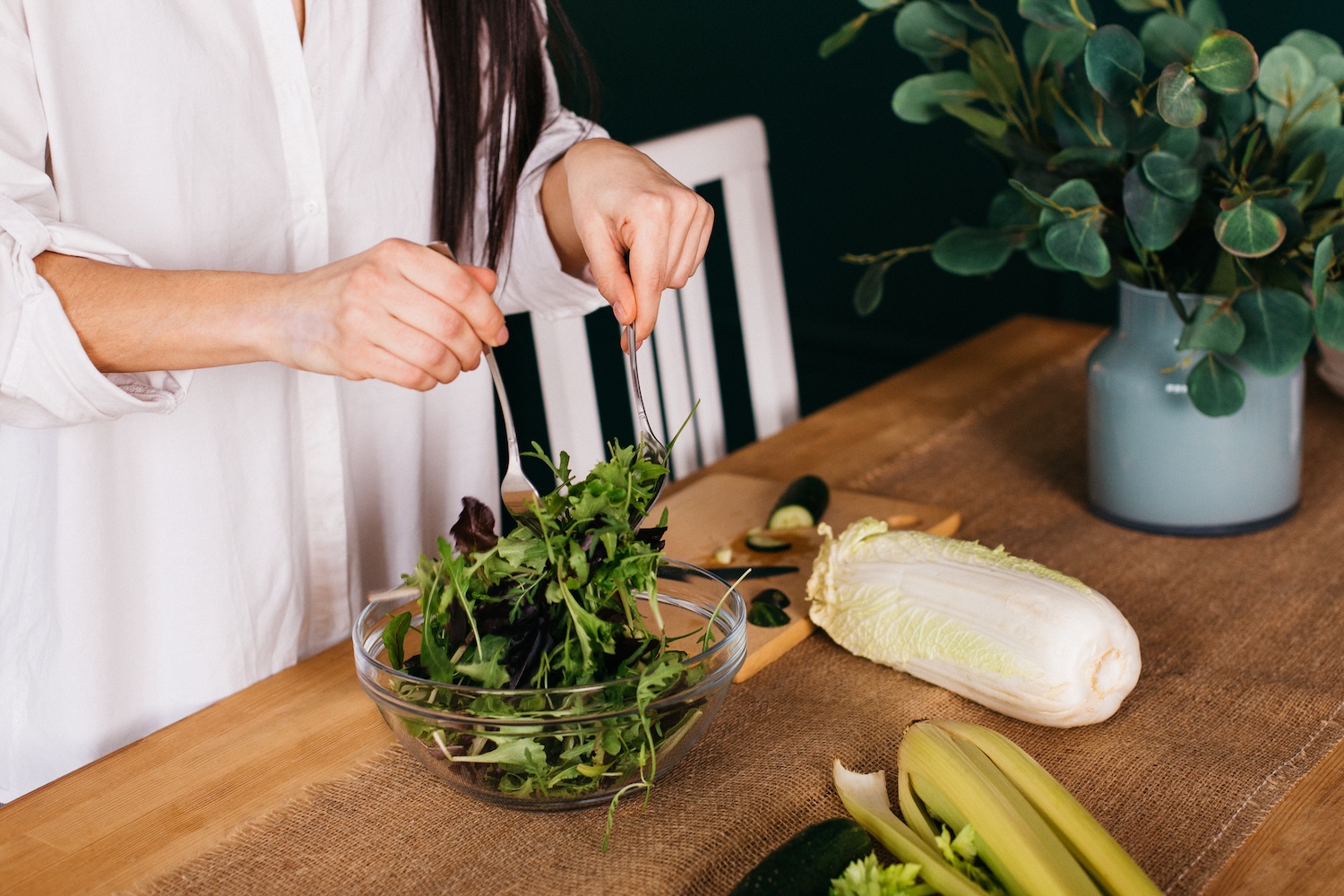 Τα χέρια μιας νεαρής γυναίκας που ετοιμάζει σαλάτα στον πάγκο της κουζίνας.