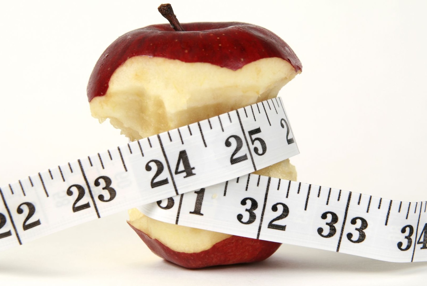 Ένα φαγωμένο μήλο όπου γύρω του είναι περιτυλιγμένη μια μεζούρα μέτρησης.