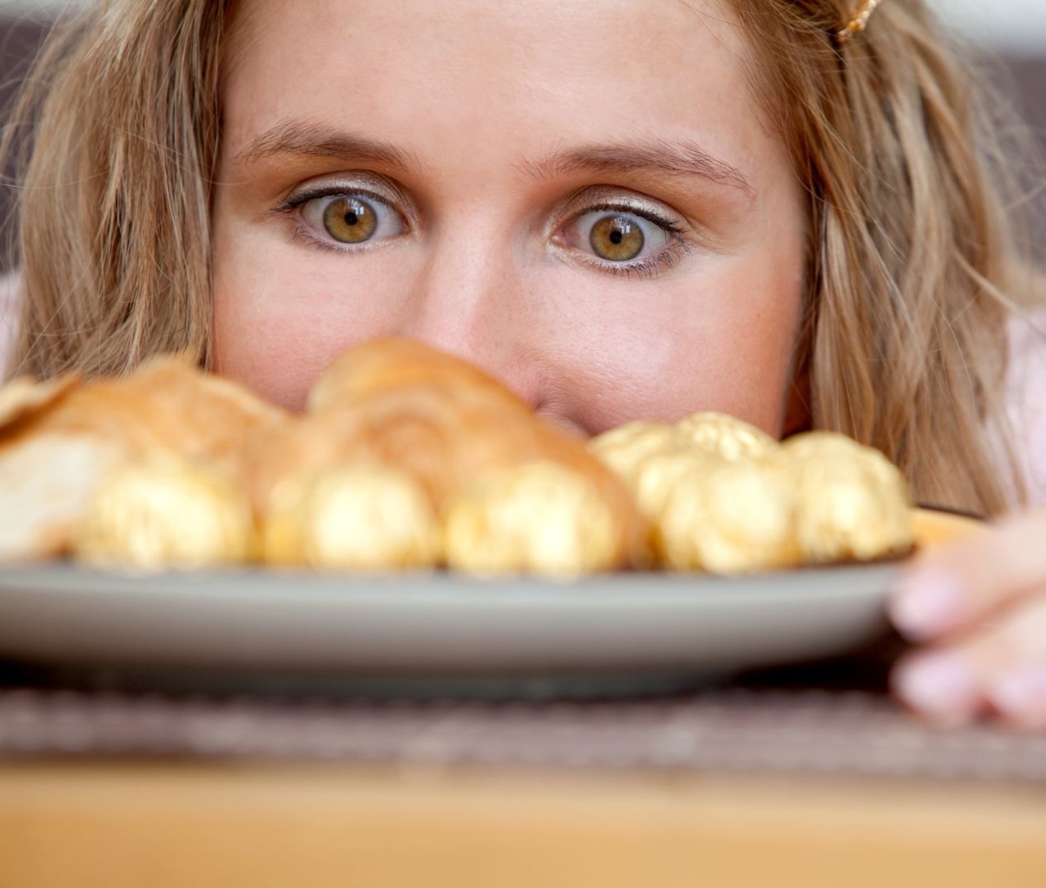 Κοντινό πλάνο μιας γυναίκας που κοιτάζει από πολύ κοντά με μεγάλη επιθυμία ένα πιάτο με γλυκά.